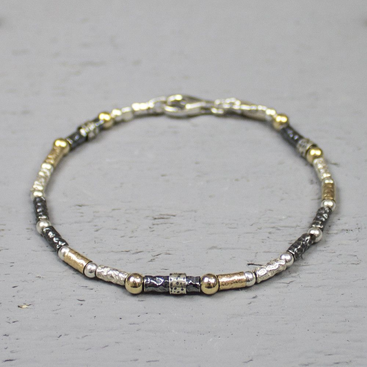 Armband gemaakt van 925 sterling zilver, geoxideerd zilver en goldfilled. Deze armband is een uitbreiding op de 17710, heeft afwisselend de eerder genoemde metaalsoorten en is bewerkt met een lichte hamerslag. Over een aantal schakels zit een zi