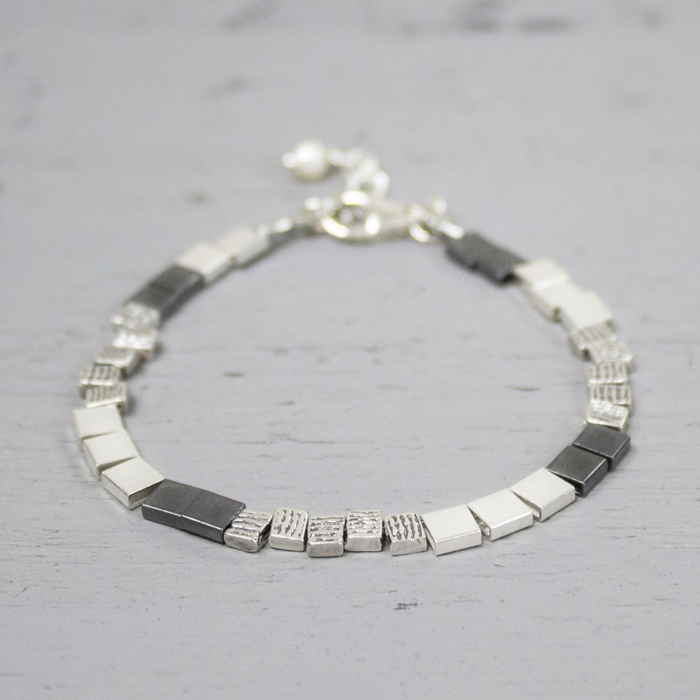 Armband van glanzend 925 sterling zilver gecombineerd met stoer geoxideerd zilver en geometrische blokjes. Een krachtig en speels sieraad met een moderne uitstraling.