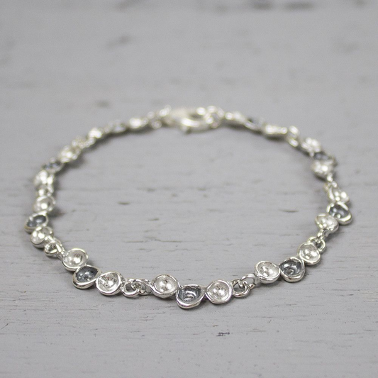 Deze armband behorend bij collier 19437 en is evenals het collier uit de collectie van 2004. De armband bevat schakels bestaande uit drie druppels, waarvan de middelste geoxideerd is.